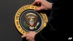 FILE - The Presidential Seal is placed on a podium in preparation for a presidential speech. With members of President Donald Trump's inner circle under investigation for possible Russia ties, questions are being asked whether, theoretically and practically, a sitting U.S. president could be charged with a crime.