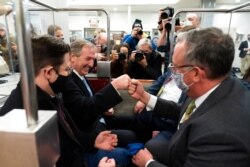 Michael van der Veen, second from left, an attorney for former President Donald Trump, fist-bumps a colleague as they depart on the Senate Subway, after Trump's acquittal in his second impeachment trial at the Capitol in Washington, Feb. 13, 2021.