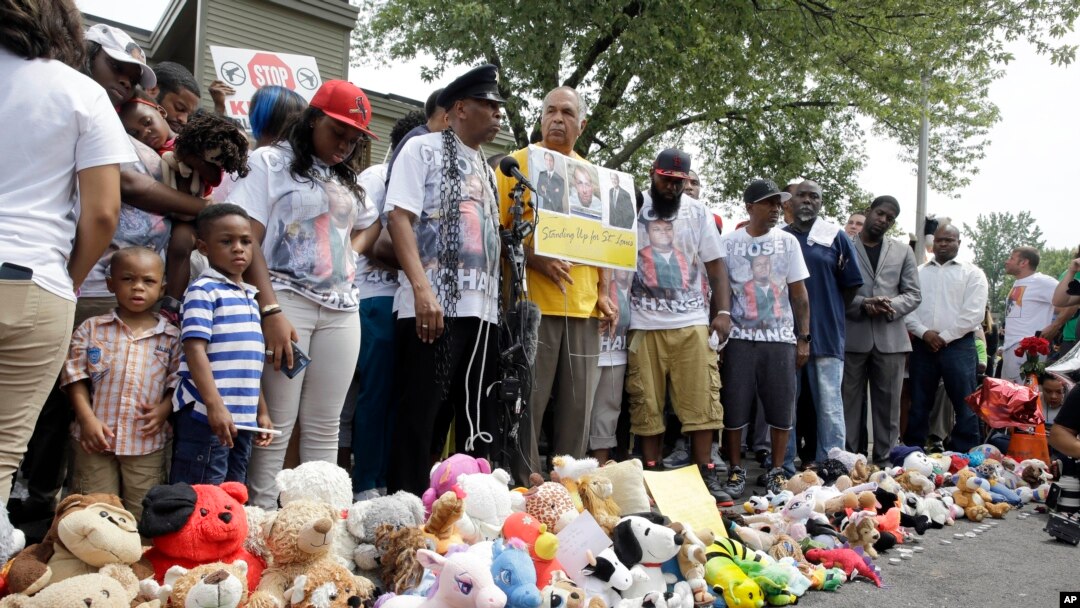 Warga kota Ferguson, Missouri mengheningkan cipta untuk mengenang kematian Michael Brown, dalam pawai hari Minggu (9/8).