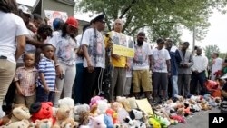 Family, friends and supporters pause for a moment of silence at a memorial to Michael Brown, Sunday, Aug. 9, 2015, in Ferguson, Missouri.