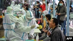 FILE - A medical worker takes a swab sample from a resident to be tested for the COVID-19 coronavirus in Wuhan in China's central Hubei province on May 14, 2020.