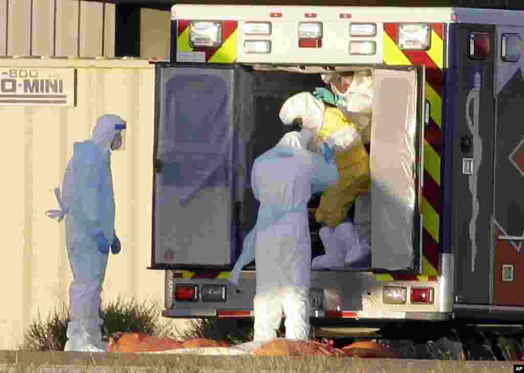 Medical staff in protective gear escort Nina Pham, exiting the ambulance, to a nearby aircraft at Love Field, Dallas, Oct. 16, 2014.