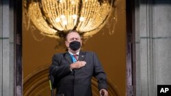 El presidente de Guatemala, Alejandro Giammattei, con una mascarilla protectora como precaución contra la propagación del nuevo coronavirus, canta el himno nacional durante la celebración del día de la independencia en la Ciudad de Guatemala.