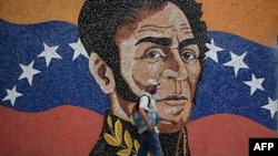 Un hombre con una máscara facial pasa junto a un mural que representa al héroe de la independencia sudamericana Simón Bolívar en Caracas el 17 de abril de 2020.