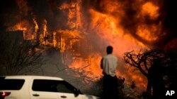 A man watches flames consume a residence as a wildfire rages in Ventura, Calif., Dec. 5, 2017. 