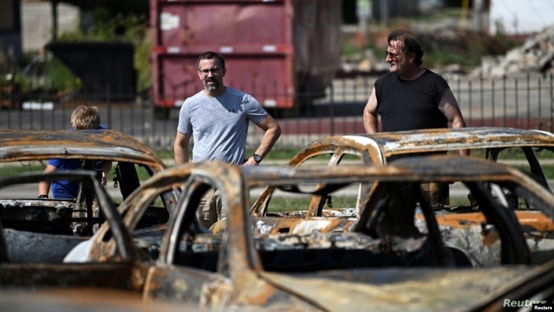 Residentes de Kenosha, Wisconsin, observan los daños ocasionados a un lote de autos usados tras las protestas raciales.