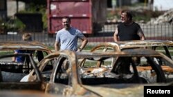 Residentes de Kenosha, Wisconsin, observan los daños ocasionados a un lote de autos usados tras las protestas raciales.