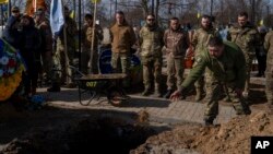 Ukrainian serviceman throws soil into the grave of Yehor Voloshyn, 27, Ukrainian serviceman, during the funeral ceremony in Pavlohrad, Dnipropetrovsk region, Ukraine, Feb. 26, 2024. The sergeant from the 3rd Assault Brigade was killed in the fighting near Avdiivka on Feb.21, 2024