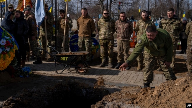 Ukrainian serviceman throws soil into the grave of Yehor Voloshyn, 27, Ukrainian serviceman, during the funeral ceremony in Pavlohrad, Dnipropetrovsk region, Ukraine, Feb. 26, 2024. The sergeant from the 3rd Assault Brigade was killed in the fighting near Avdiivka on Feb.21, 2024