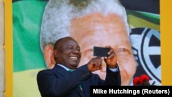 Cyril Ramaphosa utilise son téléphone lors d'un rassemblement pour commémorer l'année du centenaire de Nelson Mandela au Cap, en Afrique du Sud, le 11 février 2018.