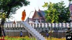 A Buddhist monk looks on from a staircase in the middle of a park in central Bangkok, Thailand.