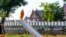 A Buddhist monk looks on from a staircase in the middle of a park in central Bangkok, Thailand.