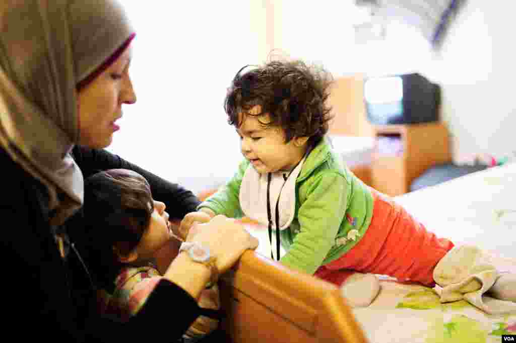 Basima Marshan, a former museum curator in Damascus, plays with her baby, Sana, while her 2-year-old daughter Sara, watches. (V. Undritz for VOA)