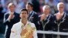 Novak Djokovic of Serbia reacts while holding the winner's trophy after defeating Roger Federer of Switzerland in their men's singles finals tennis match on Centre Court at the Wimbledon Tennis Championships in London July 6, 2014. 