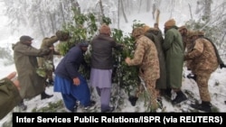 Tentara dan warga sipil membersihkan pohon dari jalan setelah hujan salju lebat di Murree, Pakistan, 8 Januari 2022. (Foto: Inter Services Public Relations/ISPR via REUTERS)