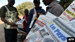 Quelques passants devant des journaux vendus dans la rue à Ouagadougou, Burkina Faso, 18 janvier 2016.