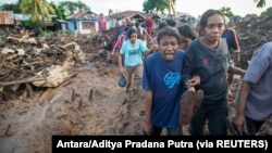 Seorang perempuan menangisi kerabatnya yang ditemukan tewas akibat banjir bandang yang dipicu hujan lebat di Flores Timur, Nusa Tenggara Timur, 6 April 2021. (Foto: Antara/Aditya Pradana Putra via REUTERS)