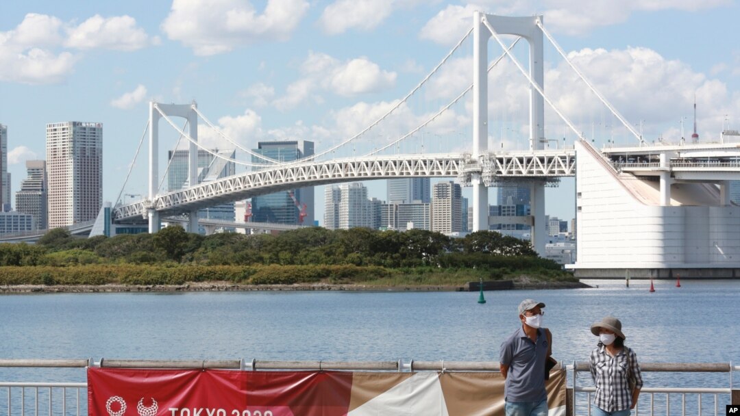 People wearing face masks to protect against the spread of the coronavirus walk at a waterfront area in Tokyo, Monday, Sept. 28, 2020. 