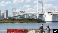 People wearing face masks to protect against the spread of the coronavirus walk at a waterfront area in Tokyo, Monday, Sept. 28, 2020. 