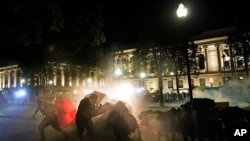 Protesters take cover from tear gas fired by police outside the Kenosha County Courthouse, Aug. 24, 2020; in Kenosha, Wis. during a second night of clashes after the police shooting of Jacob Blake a day earlier.