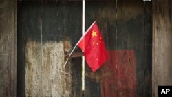 FILE - A Chinese national flag is displayed in a traditional alleyway in Beijing, China, July 7, 2024. 