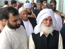 Mohammad Rafiq (R), one of the members of the congregation who stopped the attacker at a mosque, listens as people speak to media next to the Thon Oslofjord hotel in Sandvika, Norway, Aug. 11, 2019.