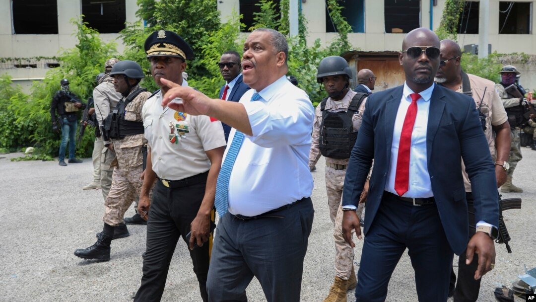 FILE - Haitian interim Prime Minister Garry Conille points as he walks with Police Chief Normil Rameau, left, in Port-au-Prince, Haiti, July 9, 2024. 