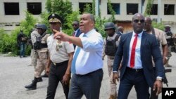 Haitian Prime Minister Garry Conille points as he walks with Police Chief Normil Rameau, left, while surrounded by security during their visit to the General Hospital in Port-au-Prince, Haiti, July 9, 2024. 