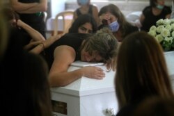 The mother of Nicole al-Helou, who was killed by the explosion Tuesday that hit the seaport of Beirut, mourns on her daughter's coffin during her funeral, in Sarba village, southern Lebanon, Aug. 6, 2020.
