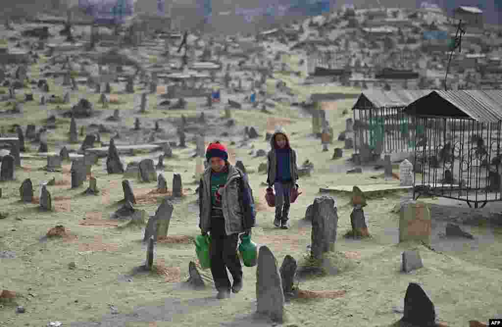 Afghan children who work as water vendors search for customers at the Kart-e-Sakhi cemetery in Kabul.