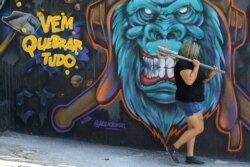 Luciana Holanda walks in front of the Rage Room, a place where people can vent their anger on everyday items, such as bottles, broken TV sets and other electronic devices, in Sao Paulo, Brazil, Feb. 19, 2021. Sign reads: "Come break everything."