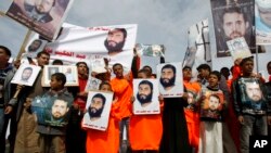 Demonstran Yaman membawa foto orang-orang yang ditahan di Guantanamo di luar Kedutaan Besar AS di Sanaa, Yaman, menuntut pembebasan 6 warga Yaman yang ditahan di Guantanamo, Sabtu, 11 Januari 2014. (Foto: AP Photo/Hani Mohammed)