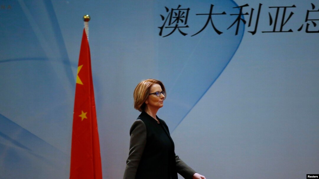 Thủ tướng Australia Julia Gillard đi ngang quốc kỳ của Trung Quốc khi bà đến dự bữa ăn trưa của Diễn đàn Kinh tế và Thương mại Trung Quốc-Australia tại một khách sạn ở Bắc Kinh, ngày 9/4/2013. 