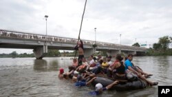 Sejumlah migran Amerika Tengah melintasi Sungai Suchiate dengan rakit, di perbatasan antara Guatemala dan Meksiko, di Ciudad Hidalgo, Meksiko, Sabtu (20/10).