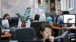 FILE - Kyiv Post chief editor Brian Bonner, right, and other journalists work at their desks in Kiev, Ukraine, Dec. 8, 2017. 