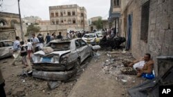 A man rests next to his car destroyed by Saudi-led airstrikes in Sana'a, Yemen, May 27, 2015.