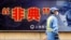 City employee wearing protective mask walks past local government anti-SARS advertisement, Shanghai, Dec. 29, 2003.