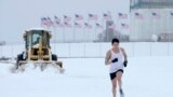 Snow is plowed behind a jogger running on the Washington Monument grounds in Washington. Snow fell in parts of the Mid-Atlantic and Northeast as winter-weary motorists faced another potentially treacherous commute, just days before the start of spring.