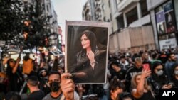 FILE - A protester holds a portrait of Mahsa Amini during a demonstration in support of the young Iranian woman, who died after being arrested in Tehran by the Islamic Republic's morality police, on Istiklal Avenue in Istanbul, Sept. 20, 2022.