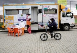 Un hombre en bicicleta pasa por un punto de salud para pruebas rápidas de antígenos, en medio del brote de la enfermedad por coronavirus (COVID-19) en El Alto, Bolivia, 16 de enero de 2021.