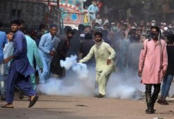 A supporters of Tehreek-e-Labiak Pakistan, a banned Islamist party, prepares to hurl back a tear gas canister fired by police to disperse protests over the arrest of their party leader Saad Rizvi, in Karachi, Pakistan, Monday, April 19, 2021. The…