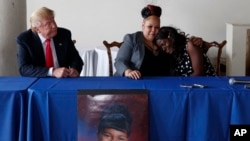 Republican presidential candidate Donald Trump, left, looks on as Shalga Hightower, center, hugs family spokesman Charmil Davis during a meeting, Sept. 2, 2016, in Philadelphia. Hightower's daughter, Iofemi Hightower, was murdered in a 2007 attack at a Ne