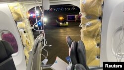 FILE - Passenger oxygen masks hang from the roof next to a missing window and a portion of a side wall of an Alaska Airlines Flight 1282, in Portland, Oregon.