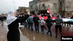 A woman throws rice as other members of the Druze community holding a Syrian flag walk past during a rally marking Syria's Independence Day in the Druze village of Buqata on the Golan Heights, April 17, 2013.