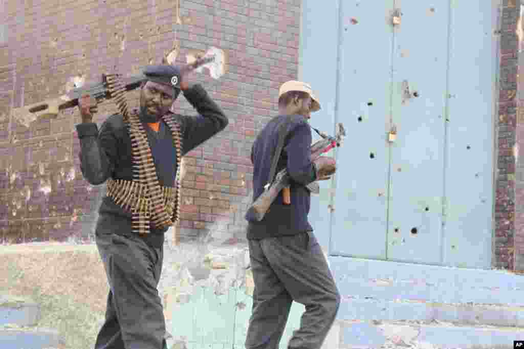 Two pro-government militiamen pass a bullet-pocked building in the deserted Bakara Market. (VOA - P. Heinlein)