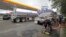 FILE - People wait in line as fuel is pumped from two tanker trucks at a convenience store in Wilmington, N.C., Sept. 17, 2018.