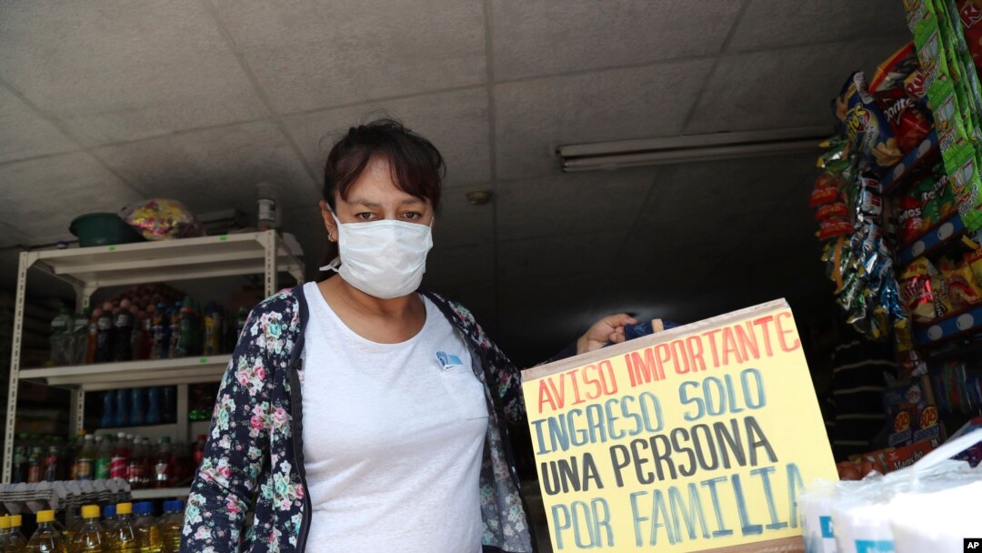 Una persona sale de un comercio que alerta sobre restricciones al ingreso de clientes en Quito.