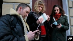 Greenpeace International activists, from left: Philip Ball of the United Kingdom, Sini Saarela of Finland and Alexandra Harris of the United Kingdom show their passports with permissions to leave Russian St.Petersburg, Russia, Dec. 26, 2013 (AP Photo/Dmitry Lovetsky)