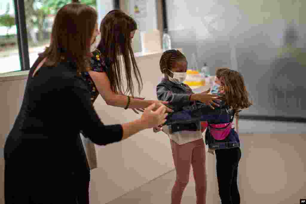 Teachers try to prevent the hug between Wendy Otin, 6, and Oumou Salam Niang, 6, as they meet on the first day of school after the lockdown, at a primary school in Barcelona, Spain.