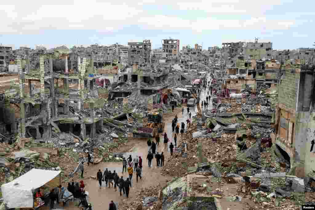 Palestinians locomotion  past   the rubble of buildings destroyed during the Israeli offensive, connected  a rainy time  successful  Gaza City amid a ceasefire betwixt  Israel and Hamas.